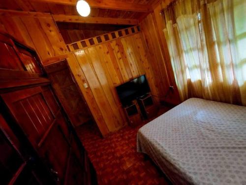 a small bedroom with a bed and a television at Cabaña Emperador – The place for QUETZALS lovers! in El Copey