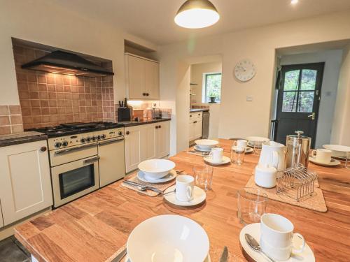 una cocina con una mesa de madera con platos blancos. en Portobello, en Grange-over-Sands