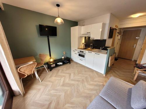 une cuisine avec des armoires blanches et un salon dans l'établissement Studio Rénové avec Balcon, Centre Station, 2 Pers, Accès Direct Pistes et Commerces - FR-1-598-109, aux Gets