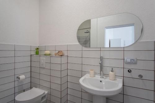 ein weißes Badezimmer mit Waschbecken und Spiegel in der Unterkunft Seaside house for families with children Mandre, Pag - 22604 in Kolan