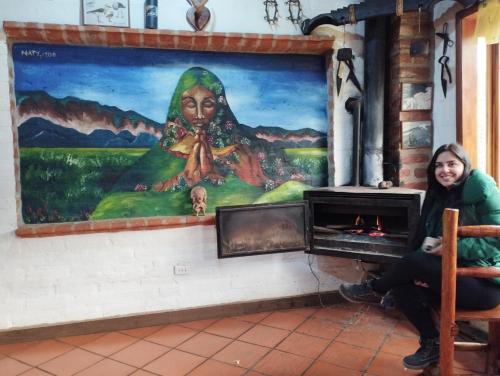 a woman sitting in front of a painting at Chakana templo de montaña in Chimborazo
