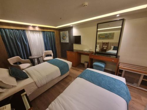 a hotel room with two beds and a mirror at Nile Cruise luxury boat Every Saturday From Luxor & Every Wednesday from Aswoan in Aḑ Ḑab‘īyah