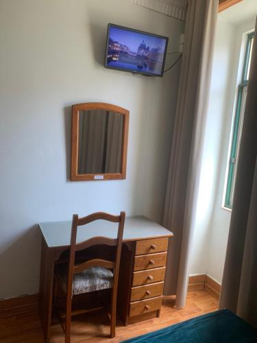 a desk with a chair and a television on a wall at Residencial Roxi in Lisbon