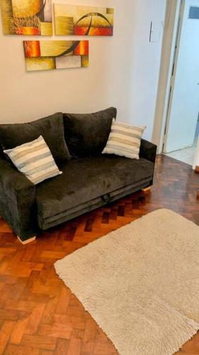a black couch sitting in a living room with a rug at Hermoso Departamento con Balcón Obelisco II in Buenos Aires