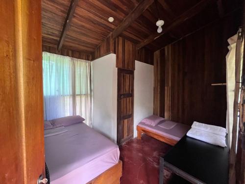 Habitación pequeña con 2 camas y ventana en Shiosai Retreat Cabins, en Gandoca