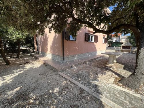 a building with a bench next to a tree at Holiday house with a parking space Simuni, Pag - 22608 in Kolan