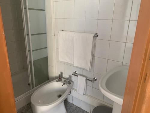 La salle de bains blanche est pourvue de toilettes et d'un lavabo. dans l'établissement Residencial Roxi, à Lisbonne