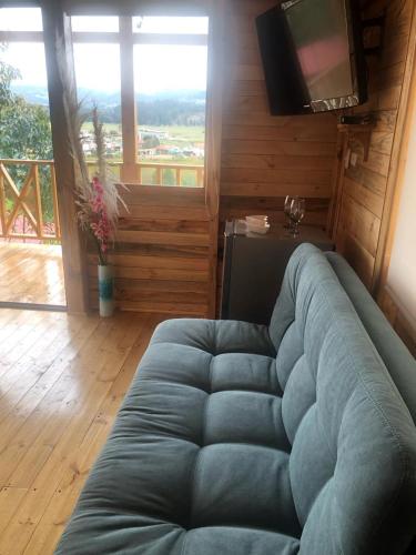 ein blaues Sofa im Wohnzimmer mit TV in der Unterkunft Cabaña Monarca in Paipa