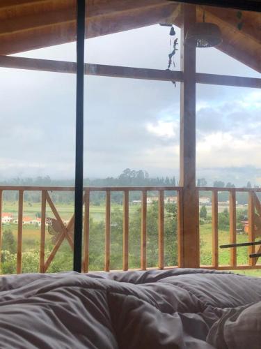 Schlafzimmer mit Blick auf ein Feld aus dem Fenster in der Unterkunft Cabaña Monarca in Paipa