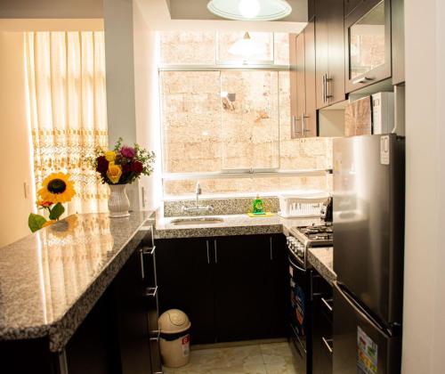 a kitchen with a sink and a refrigerator at Departamento Familiar Equipado in Cusco