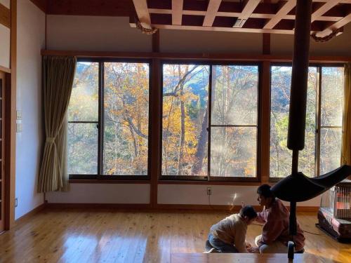 Irori 新山ふるさと体験館 في إينا: طفلين يلعبون في غرفة مع نوافذ كبيرة