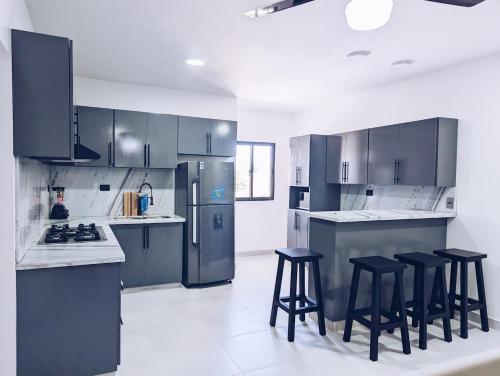 a kitchen with stainless steel appliances and black stools at Apartment in Sosua - 4 Minutes From The Airport in San Felipe de Puerto Plata