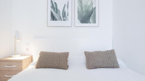 1 dormitorio con 1 cama blanca y 2 cuadros en la pared en Casa Vesalia a 1a línea de mar con AA y Wi-Fi. en Vinarós