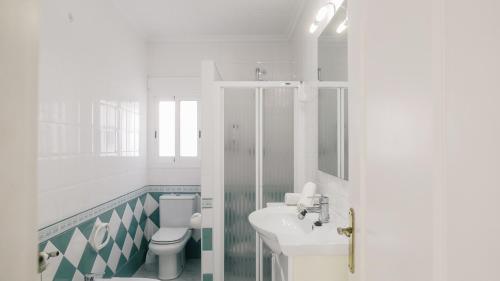 een witte badkamer met een toilet en een wastafel bij Casa Vesalia a 1a línea de mar con AA y Wi-Fi. in Vinarós