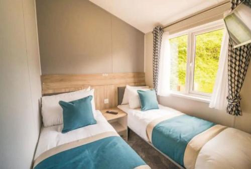 2 camas en una habitación pequeña con ventana en Sandy Bay Lodge, en Newbiggin-by-the-Sea