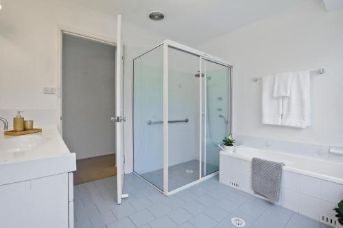uma casa de banho com uma cabina de duche em vidro e uma banheira em Casa del Sol em Kiama