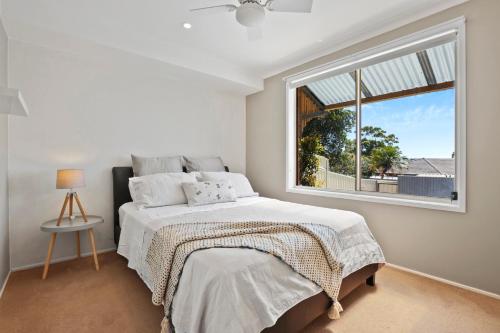 um quarto branco com uma cama e uma janela em Casa del Sol em Kiama