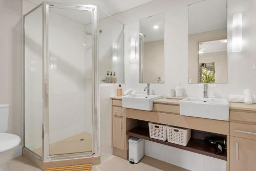 a bathroom with two sinks and a shower at Coastal Bliss - Cairns 9 Pools BBQ & Gym in Westcourt