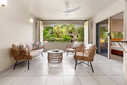 a living room with chairs and a couch and a table at Coastal Bliss - Cairns 9 Pools BBQ & Gym in Westcourt