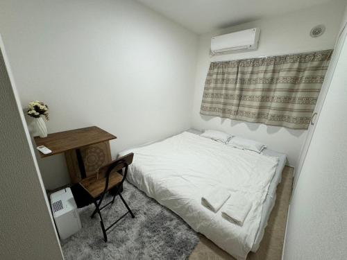 Habitación pequeña con cama y escritorio. en NANA HOUSE, en Tokio