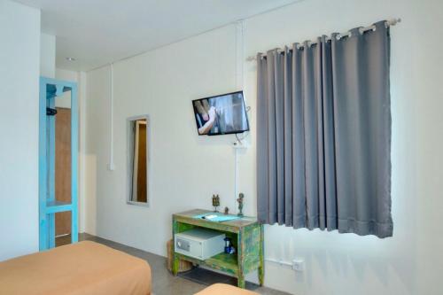 um quarto com uma cama e uma televisão na parede em A7 Guesthouse em Canggu