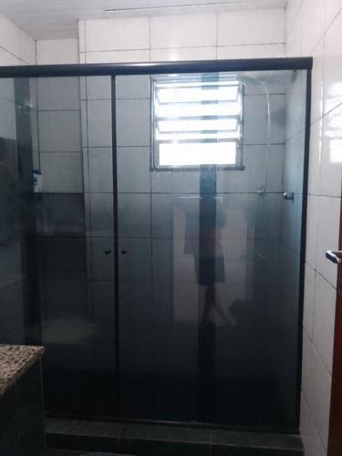 uma porta de duche envidraçada com uma janela na casa de banho em Casa Grande e Confortável no Rio de Janeiro