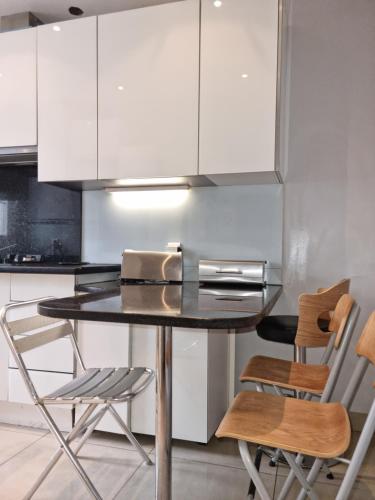 une cuisine avec des armoires blanches et une table et des chaises dans l'établissement APPARTEMENT 2 CHAMBRE A 10 MINUTE DU CENTRE DE PARIS, à Clichy