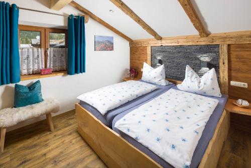 a bedroom with a large bed with blue curtains at Gästehaus Kaltbachhäusl Garni in Ramsau