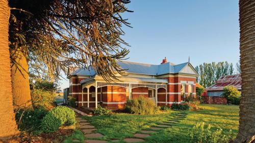 a red brick house with a tree in front of it at The Royal Standard Farm Daylesford in Daylesford