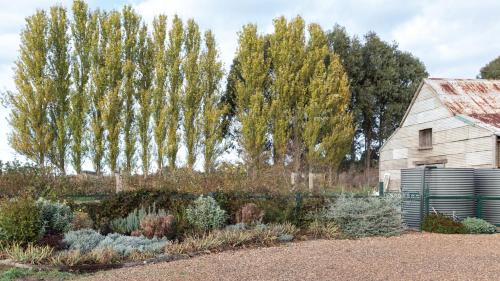 a garden with a barn and trees in the background at The Royal Standard Farm Daylesford in Daylesford