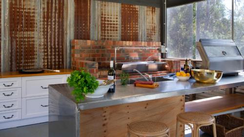 a kitchen with a sink and a counter with stools at Kangaroo Creek Estate Daylesford in Glenlyon