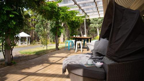 a patio with a bed and a table and trees at Forest Estate Daylesford in Glenlyon