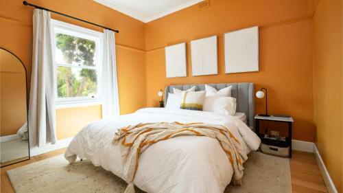 a bedroom with a bed with orange walls and a window at Higgins House in Hepburn Springs