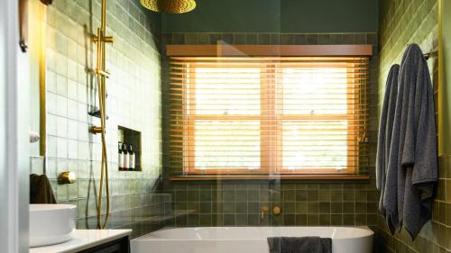 a bathroom with a tub and a sink and a window at Higgins House in Hepburn Springs