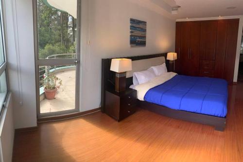 una camera con un letto blu e una finestra di Departamento frente al Centro Corporativo Ekopark a Quito