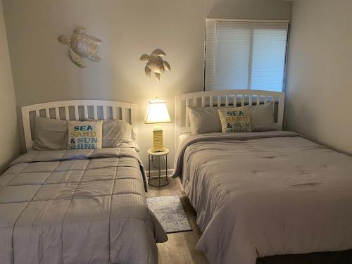 a bedroom with two beds and a lamp and a window at Large Myrtle Beach Condo, Fully Renovated in Myrtle Beach