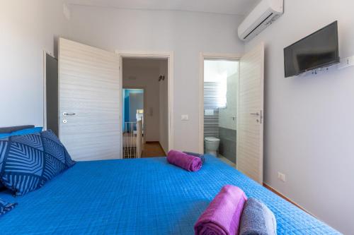 una camera da letto con un letto blu con cuscini viola di Ibla nel Cuore a Ragusa