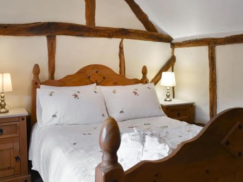 a bedroom with a wooden bed with white sheets at Cobblers Retreat in Birley