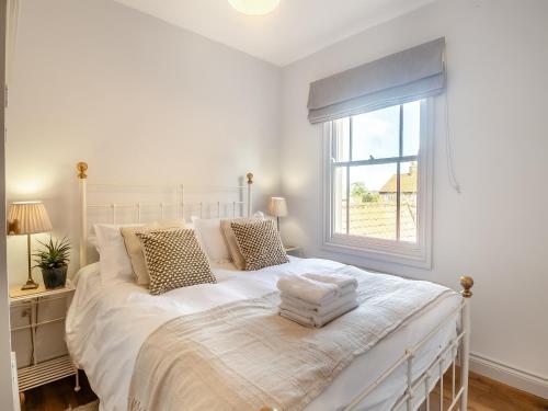 a bedroom with a white bed with a window at Hardys Cottage in Overstrand