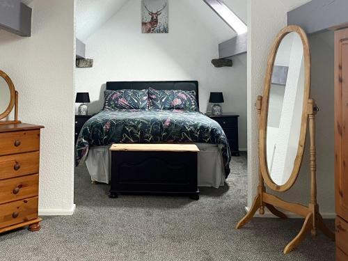 a bedroom with a bed and a large mirror at Dairy Cottage - 28344 in Staintondale
