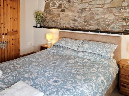 een bed in een slaapkamer met een stenen muur bij Y Dderwen At Brynglas Farm in Llanfair Caereinion