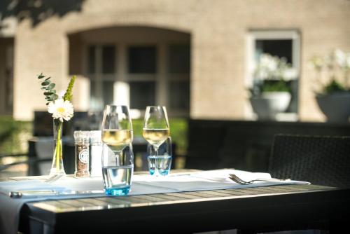 a table with two glasses of white wine on it at Golden Tulip Ampt van Nijkerk in Nijkerk