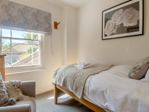 a bedroom with a bed and a window and a chair at Forsythia House in Overstrand