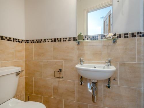 a bathroom with a sink and a toilet and a mirror at Forsythia House in Overstrand