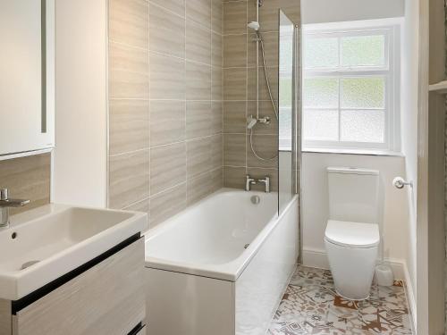 a bathroom with a tub and a toilet and a sink at Windward House in Salcombe