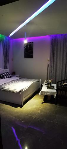 1 dormitorio con cama, mesa y luces púrpuras en منتجع سمايل القريات, en Al-Qurayat