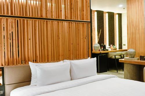1 dormitorio con 1 cama con pared de madera en Azzurro Hotel, en Ángeles