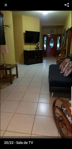 a living room with a tv and a tiled floor at Little paradise in Tela