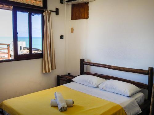 a bedroom with a bed with a yellow blanket and a window at Apart Hotel Casa Grande in Natal