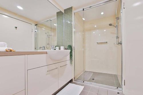 a white bathroom with a shower and a sink at Loka Santi 10 - Beachfront unit in Agnes Water